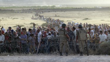 turkish-soldiers-stand-guard-syrian-refugees-wait-behind-border-fences